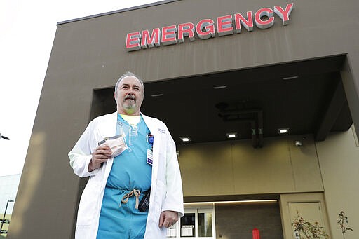 Dr. Stephen Anderson, a physician who works in the Emergency Department at the MultiCare Auburn Medical Center in Auburn, Wash., holds his mask and face shield as he poses for a photo before starting his shift, Tuesday, March 17, 2020, in Auburn, Wash., south of Seattle. Anderson said he writes messages on his shields to identify them as his, and this morning he chose the phrase &quot;Stay Safe.&quot; &#147;There just are not enough masks to go around at my hospital,&#148; said Dr. Anderson. &quot;I've got a two-day supply of masks so we're trying to be conservative. You get one in the morning. You clean it and reuse it.&quot; (AP Photo/Ted S. Warren)