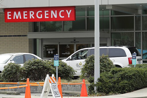 A vehicle from the Life Care Center at Kirkland that was picking up a wheelchair is parked at the EvergreenHealth Medical Center, Tuesday, March 17, 2020, in Kirkland, Wash., near Seattle. In the area that has led the country in coronavirus cases and also across the country, hospitals are gearing up for an onslaught of coronavirus patients, but staff on the front lines are stretched thin and don't have the equipment they need to protect themselves from the highly contagious virus. (AP Photo/Ted S. Warren)