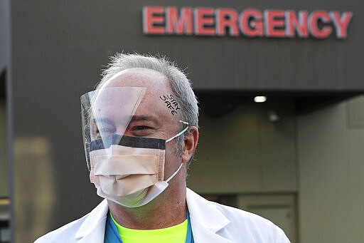 Dr. Stephen Anderson, a physician who works in the Emergency Department at the MultiCare Auburn Medical Center in Auburn, Wash., wears a mask and face shield as he poses for a photo before starting his shift, Tuesday, March 17, 2020, in Auburn, Wash., south of Seattle. Anderson said he writes messages on his shields to identify them as his, and this morning he chose the phrase &quot;Stay Safe.&quot; &#147;There just are not enough masks to go around at my hospital,&#148; said Dr. Anderson. &quot;I've got a two-day supply of masks so we're trying to be conservative. You get one in the morning. You clean it and reuse it.&quot; (AP Photo/Ted S. Warren)