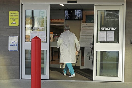 Dr. Stephen Anderson, a physician who works in the Emergency Department at the MultiCare Auburn Medical Center in Auburn, Wash., carries his mask as he walks into the emergency entrance to begin his shift, Tuesday, March 17, 2020, in Auburn, Wash., south of Seattle. Anderson said he writes messages on his shields to identify them as his, and this morning he chose the phrase &quot;Stay Safe.&quot; &#147;There just are not enough masks to go around at my hospital,&#148; said Dr. Anderson. &quot;I've got a two-day supply of masks so we're trying to be conservative. You get one in the morning. You clean it and reuse it.&quot; (AP Photo/Ted S. Warren)