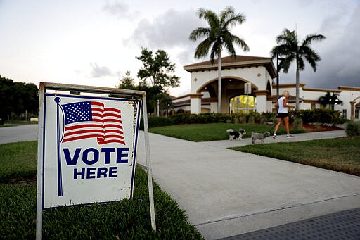 A sign is placed outside of a polling place at the Boca Raton Library during the Florida primary election, Tuesday, March 17, 2020, in Boca Raton, Fla.  As Florida officials try to contain the spread of the novel coronavirus, the state's voters will head to the polls and cast ballots in the Democratic presidential primary.   (AP Photo/Julio Cortez)