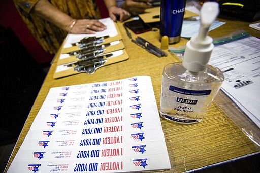 Hand sanitizer and stickers are set up at the Lincoln Lodge Polling Station, 1st ward, Tuesday, March 17th, 2020 in Chicago.  Voters across the state are getting the chance to decide competitive primary races for the U.S. House and the Illinois Supreme Court, with concerns about the coronavirus looming large. Election officials have been promoting voting early and casting ballots by mail in an attempt to control crowds and curb the spread. The vast majority of people recover from the new coronavirus. According to the World  Health Organization, most people recover in about two to six weeks, depending on the severity of the illness. ( James Foster/Chicago Sun-Times via AP)