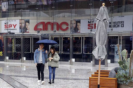 People exit an AMC theater Saturday, March 14, 2020, in Los Angeles. Californians wanting to escape the new reality of the coronavirus at the movies, casino or amusement park are running into the six-foot rule. State health officials issued new guidance Saturday urging theaters to keep attendance under 250 people and ask strangers to sit six feet apart. (AP Photo/Marcio Jose Sanchez)