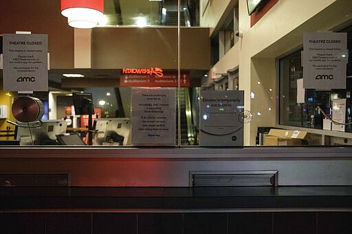 Signs hang in the ticket window of a movie theater notifying customers that it is closed, Monday, March 16, 2020 in New York. New York state entered a new phase in the coronavirus pandemic Monday joining with Connecticut and New Jersey to close bars, restaurants and movie theaters starting Monday night. The governors said restaurants and bars will move to take-out and delivery services only. The three states also will limit crowd capacity for social and recreational gatherings to 50 people, effective 8 p.m. (AP Photo/Yuki Iwamura)