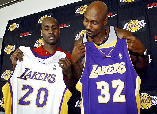 FILE - In this July 17, 2003 file photo Gary Payton, left, and Karl Malone display their new Los Angeles Lakers' jerseys during a news conference at the Staples Center in Los Angeles. The two players signed with the Lakers as free agents. Tom Brady&#146;s departure from the New England Patriots on Tuesday, March 17, 2020, brings an end to one of the NFL&#146;s most memorable eras. That&#146;s happened plenty of times before in sports &#151; a legendary star switching teams toward the end of his career. Malone was hoping for a triumphant ending when he signed with the Lakers in 2003 after 18 stellar seasons in Utah. But he came up just short in his quest for a title when the Lakers lost to Detroit in the 2004 NBA Finals. (AP Photo/Ric Francis, file)