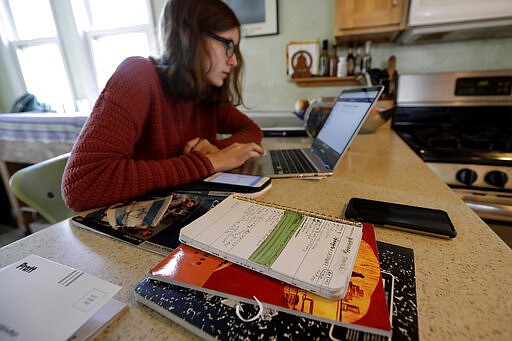 Olivia Marton, an 11th grader at Lincoln Park High School, studies school work with her computer at her home in Chicago, Tuesday, March 17, 2020. Illinois Gov. J.B. Pritzker's executive order closes all kindergarten through 12th grade schools &#151; public and private &#151; &quot;for educational purposes&quot; from March 17 through March 30, due to caronavirus, with students returning to classes March 31. Some individual districts, and some other states, have chosen to keep schools closed longer than that. (AP Photo/Nam Y. Huh)