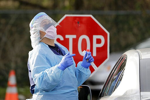 Theresa Malijan, a registered nurse, demonstrates to a patient how to hold their head before she uses a swab to take a sample at a drive-through COVID-19 testing station for University of Washington Medicine patients Tuesday, March 17, 2020, in Seattle. The appointment-only drive-through clinic began a day earlier. Health authorities in Washington reported more COVID19 deaths in the state that has been hardest hit by the outbreak. (AP Photo/Elaine Thompson)