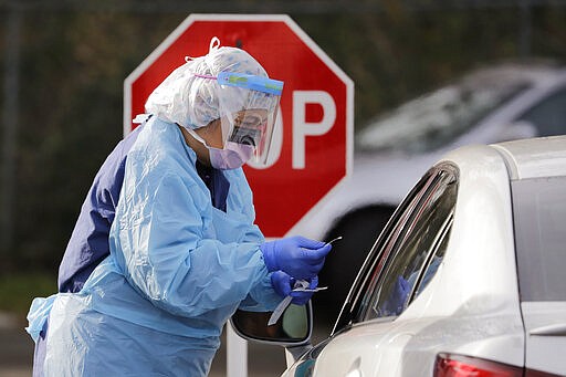 Theresa Malijan, a registered nurse, completes taking a nasopharyngeal swab from a patient at a drive-through COVID-19 testing station for University of Washington Medicine patients, Tuesday, March 17, 2020, in Seattle. The appointment-only drive-through clinic began a day earlier. Washington leads the country in the number of deaths, with most being associated with a nursing home in Kirkland. By Monday, the number of positive cases topped 900.
(AP Photo/Elaine Thompson)