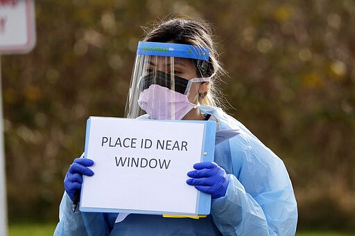 Medical assistant Miriam Fuentes gives a patient instructions via sign at a drive-through COVID-19 coronavirus testing station for University of Washington Medicine patients Tuesday, March 17, 2020, in Seattle. The appointment-only drive-through clinic began a day earlier. Health authorities in Washington reported more COVID19 deaths in the state that has been hardest hit by the outbreak. (AP Photo/Elaine Thompson)