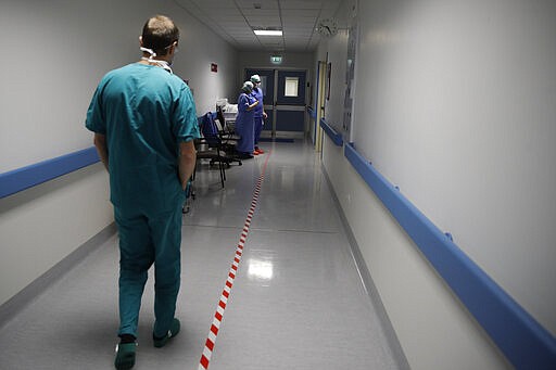 In this March 16, 2020, photo, Sergio Cattaneo, head of the anesthesia and resuscitation unit of the Brescia Spedali Civili hospital, walks to the ICU room, in Brescia, Italy. Three weeks into Italy&#146;s coronavirus crisis, Cattaneo has seen an unused ward outfitted into an intensive care unit in six days, a hospital laundry room converted into a giant stretcher-filled waiting room and a tented field hospital erected outside to test possible new virus patients. (AP Photo/Luca Bruno)