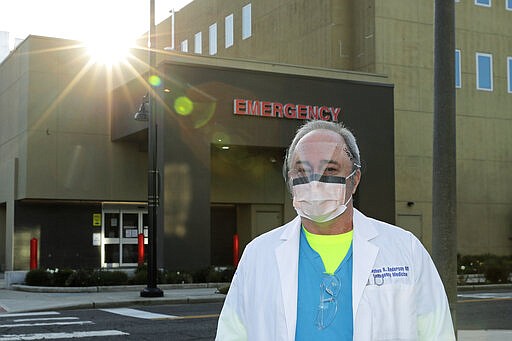 Dr. Stephen Anderson, a physician who works in the Emergency Department at the MultiCare Auburn Medical Center in Auburn, Wash., wears a mask and face shield as he poses for a photo before starting his shift, Tuesday, March 17, 2020, in Auburn, Wash., south of Seattle. Anderson said he writes messages on his shields to identify them as his, and this morning he chose the phrase &quot;Stay Safe.&quot; &#147;There just are not enough masks to go around at my hospital,&#148; said Dr. Anderson. &quot;I've got a two-day supply of masks so we're trying to be conservative. You get one in the morning. You clean it and reuse it.&quot; (AP Photo/Ted S. Warren)