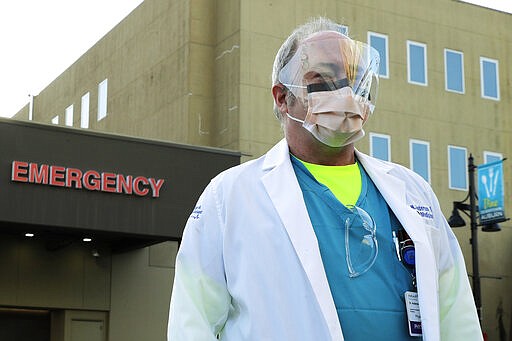 Dr. Stephen Anderson, a physician who works in the Emergency Department at the MultiCare Auburn Medical Center in Auburn, Wash., wears a mask and face shield as he poses for a photo before starting his shift, Tuesday, March 17, 2020, in Auburn, Wash., south of Seattle. Anderson said he writes messages on his shields to identify them as his, and this morning he chose the phrase &quot;Stay Safe.&quot; &#147;There just are not enough masks to go around at my hospital,&#148; said Dr. Anderson. &quot;I've got a two-day supply of masks so we're trying to be conservative. You get one in the morning. You clean it and reuse it.&quot; (AP Photo/Ted S. Warren)