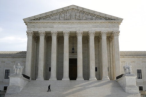 A police officer walks outside the Supreme Court in Washington, Monday, March 16, 2020. The Supreme Court announced Monday that it is postponing arguments for late March and early April because of the coronavirus, including fights over subpoenas for President Donald Trump's financial records. (AP Photo/Patrick Semansky)