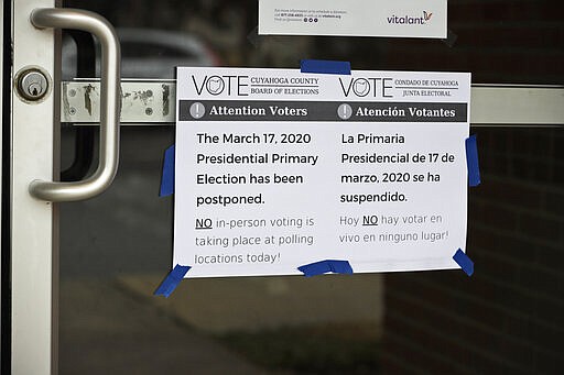 A sign is taped to a door leading into a polling location at the Messiah Lutheran Church, Tuesday, March 17, 2020, in Lyndhurst, Ohio. Ohio called off its presidential primary just hours before polls were set to open there and in three other states, an 11th-hour decision the governor said was necessary to prevent further fueling the coronavirus pandemic that has paralyzed the nation. (AP Photo/Tony Dejak)