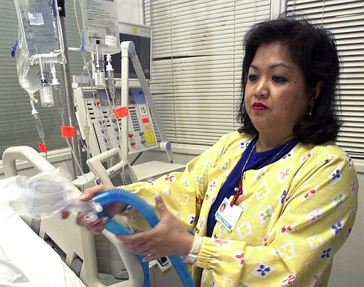 FILE - In this May 25, 2005, file photo, Lovely R. Suanino, a respiratory therapist at Newark Beth Israel Medical Center in Newark, N.J., demonstrates setting up a ventilator in the intensive care unit of the hospital. U.S. hospitals bracing for a possible onslaught of coronavirus patients with pneumonia and other breathing difficulties could face a critical shortage of mechanical ventilators and health care workers to operate them. (AP Photo/Mike Derer, File)