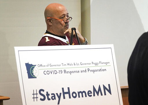 Restaurant owner Andrew Zimmern listens during a news conference in St. Paul, Minn., Monday, March 16, 2020. Minnesota Gov. Tim Walz ordered bars and restaurants across Minnesota to temporarily close to customers who dine in amid fears of coronavirus cases. (Glen Stubbe/Star Tribune via AP)