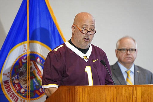 Restaurant owner Andrew Zimmern, along with Minnesota Gov. Tim Walz speaks during a news conference in St. Paul, Minn., Monday, March 16, 2020. Walz ordered bars and restaurants across Minnesota to temporarily close to customers who dine in amid fears of coronavirus cases. (Glen Stubbe/Star Tribune via AP)