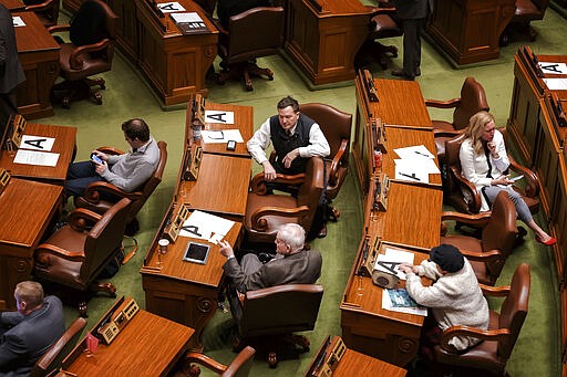 Desks and chairs where Minnesota state legislators are allowed to sit are marked with a letter A in order to keep them six feet away from each other amid concerns about the new coronavirus, forcing some to sit in the visitors gallery and in the alcoves at the back of the chamber, Monday, March 16, 2020, in St. Paul, Minn. They were all asked Monday to be on call within an hour's notice. (Glen Stubbe/Star Tribune via AP)