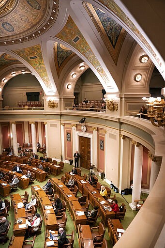 Desks and chairs where Minnesota state legislators are allowed to sit are marked with a letter A in order to keep them six feet away from each other amid concerns about the new coronavirus, forcing some to sit in the visitors gallery and in the alcoves at the back of the chamber, Monday, March 16, 2020, in St. Paul, Minn. They were all asked Monday to be on call within an hour's notice. (Glen Stubbe/Star Tribune via AP)