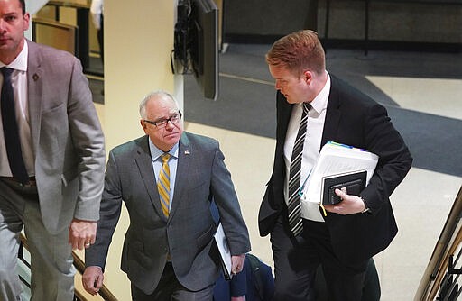 Minnesota Governor Tim Walz walked to a news conference with his chief of staff Chris Schmitter in St. Paul, Minn., Monday, March 16, 2020. Walz ordered bars and restaurants across Minnesota to temporarily close to customers who dine in amid fears of coronavirus cases.  (Glen Stubbe/Star Tribune via AP)