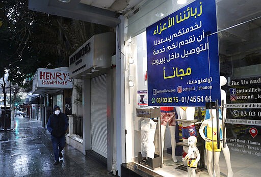 A man wears a mask passes a closed children shop with an Arabic banner that reads: &quot;Dear customers for your service we are happy to offer you free delivery inside Beirut, contact us,&quot; after most of the shops and restaurants closed as part of the preventive measures against the ongoing coronavirus pandemic, in Beirut, Lebanon, Tuesday, March 17, 2020. For most people, the virus causes only mild or moderate symptoms, such as fever and cough. For some, especially older adults and people with existing health problems, it can cause more severe illness, including pneumonia. (AP Photo/Hussein Malla)