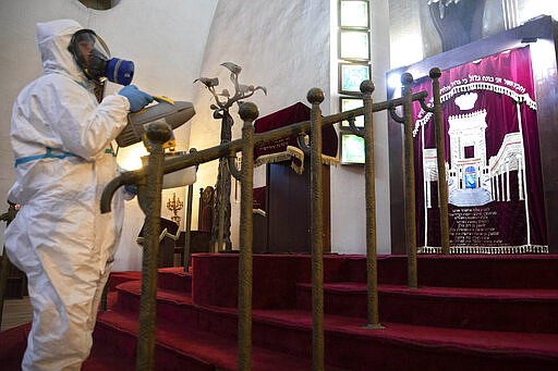 Workers spray disinfectant as a precaution against the coronavirus at the Great Synagogue in Tel Aviv, Israel, Tuesday, March 17, 2020. The head of Israel's shadowy Shin Bet internal security service said Tuesday that his agency received Cabinet approval overnight to start deploying its counter-terrorism tech measures to help curb the spread of the new coronavirus in Israel. For most people, the new coronavirus causes only mild or moderate symptoms. For some it can cause more severe illness. (AP Photo/Sebastian Scheiner)