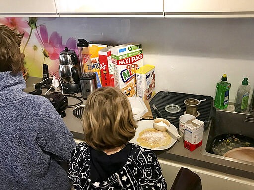 In this March 13, 2020, photo, the children of German legal practitioner Karoline Preisler, who tested positive for of the new COVID-19 respiratory disease, prepare food in the kitchen of their home in Barth, Germany. Lonely, frightened and unwell, Preisler turned to the internet for information from other patients but didn&#146;t find many first-hand accounts of living with and fighting the virus. So she decided to share her experience on Twitter. (Karoline Preisler via AP)