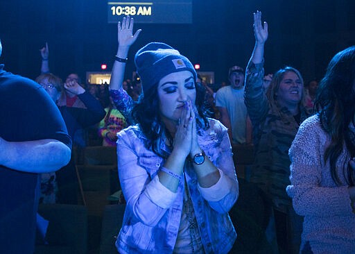 Leslie Owensby prays during worship at the beginning of service at Redemption to the Nations church on Sunday, March 15, 2020 in Chattanooga, Tenn. While most churches around Hamilton County decided to cancel services because of concerns over the COVID-19 coronavirus, Redemption to the Nations stayed open. (Troy Stolt/Chattanooga Times Free Press via AP)