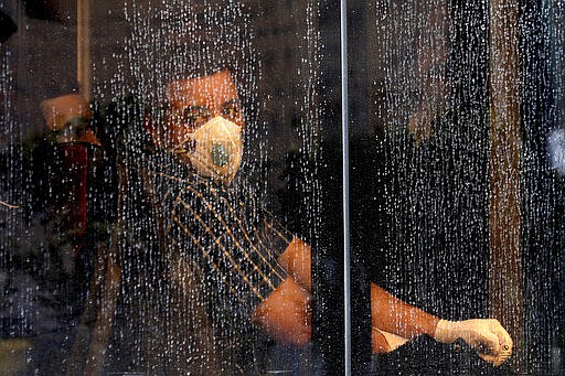 FILE &#151; In this Feb. 23, 2020 file photo, a commuter looks through a water-stained window wearing a mask and gloves to help prevent the spread of the COVID-19 virus, on a public bus in downtown Tehran, Iran. Nine out of 10 cases of the virus in the Middle East come from the Islamic Republic. Days of denials gave the virus time to spread as the country marked the 41st anniversary of its 1979 Islamic Revolution. Iran also held a parliamentary election in which authorities desperately sought to boost turnout. For most people, the new coronavirus causes only mild or moderate symptoms. For some it can cause more severe illness. (AP Photo/Ebrahim Noroozi, File)