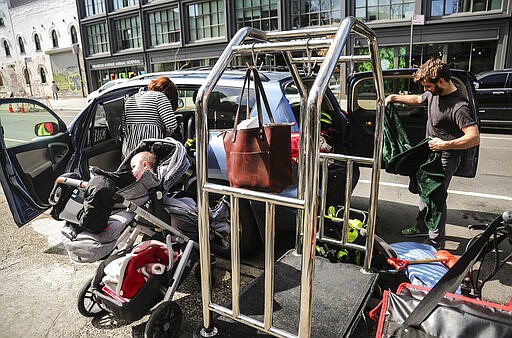 Cailin Sandvig, left, and Justin Bracken, load their family car as they prepare to leave their home in the Crown Heights area of Brooklyn, in New York, with their newborn twins, Milo, center, and Aurelia, 10 months, to avoid the spread of the new coronavirus, Monday, March, 16, 2020. &quot;We are fleeing the city,&quot; said Sandvig who works remotely for her job. &quot;We are going to end up in Wheaton, Illinois, where we have a big, old house to be in with my mom that's otherwise empty.&quot; (AP Photo/Bebeto Matthews)