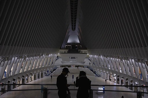 Tourists stand inside The Oculus at the World Trade Center transportation hub, Monday, March 16, 2020 in New York. New York state entered a new phase in the coronavirus pandemic Monday, joining with Connecticut and New Jersey to close bars, restaurants and movie theaters starting Monday night. The governors said restaurants and bars will move to take-out and delivery services only. The three states also will limit crowd capacity for social and recreational gatherings to 50 people, effective 8 p.m. (AP Photo/Yuki Iwamura)