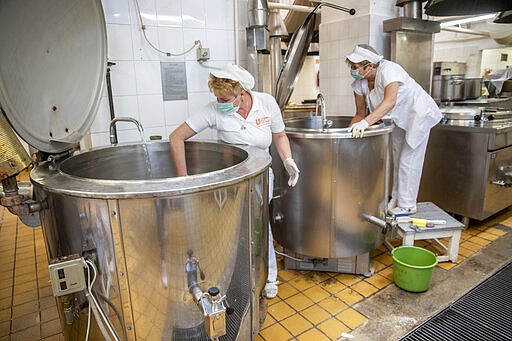 Employees in protective mask and gloves disinfect cooking facilities as a precaution against the spread of the novel coronavirus in a public kitchen for school children in Oroshaza, southeastern Hungary, Tuesday, March 17, 2020. For most people, the new coronavirus causes only mild or moderate symptoms, such as fever and cough. For some, especially older adults and people with existing health problems, it can cause more severe illness, including pneumonia. (Tibor Rosta/MTI via AP)