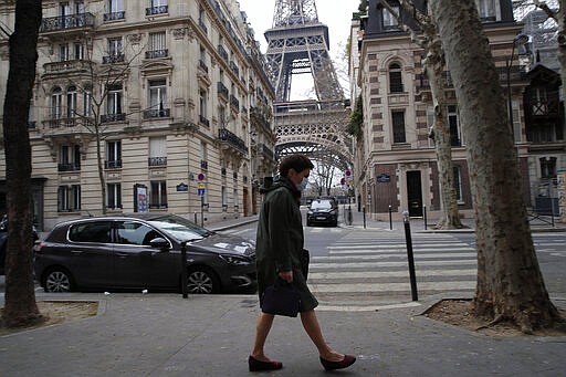 A masked woman walks in an empty street next to the Eiffel Tower, in Paris, Tuesday, March 17, 2020. French President Emmanuel Macron said that starting on Tuesday, people would be allowed to leave the place they live only for necessary activities such as shopping for food, going to work or taking a walk. For most people, the new coronavirus causes only mild or moderate symptoms. For some it can cause more severe illness. (AP Photo/Francois Mori)