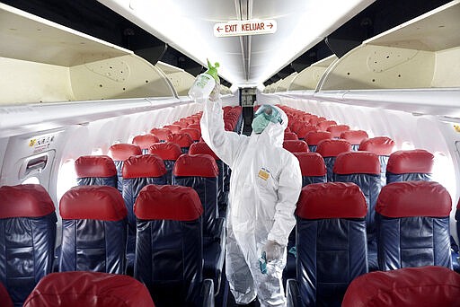 A worker sprays disinfectant inside the cabin of a Lion Air passenger jet as a precaution against the new coronavirus, at Soekarno-Hatta International Airport in Tangerang, Indonesia, Tuesday, March 17, 2020. For most people, the new coronavirus causes only mild or moderate symptoms. For some, especially older adults it can cause more severe illness. (AP Photo)