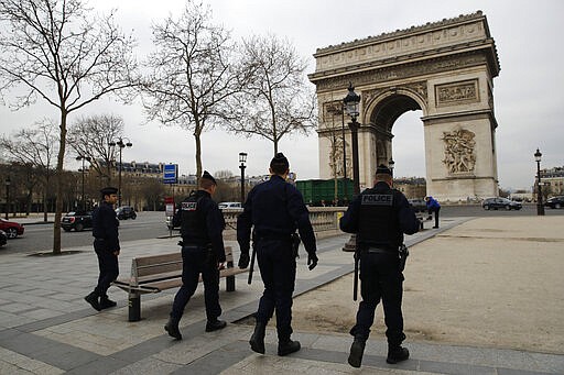 Police officers patrol on the Champs-Elysees avenue Tuesday, March 17, 2020 in Paris. French President Emmanuel Macron announced strong restrictions on freedom of movement in a bid to counter the new coronavirus, as the European Union closed its external borders to foreign travelers. For most people, the new coronavirus causes only mild or moderate symptoms. For some it can cause more severe illness. (AP Photo/Christophe Ena)