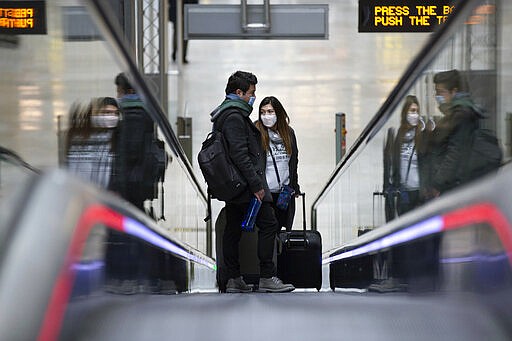 Passengers wear face masks at Adolfo Suarez-Barajas international airport, outskirts Madrid, Spain, Tuesday, March 17, 2020. Millions of people are holing up at home, stocking up on supplies and keeping a wary eye on how close they get to friends and neighbors as the coronavirus spreads to more places. For most people, the new coronavirus causes only mild or moderate symptoms. For some it can cause more severe illness. (AP Photo/Manu Fernandez)