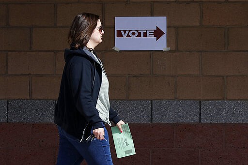 An Arizona voter delivers her mail-in ballot at a polling station for the Arizona presidential preference election Tuesday, March 17, 2020, in Phoenix. (AP Photo/Matt York)