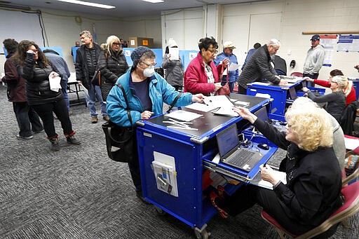 Chicago residents line up for early voting at the Roden Library Monday, March 16, 2020, in Chicago. (AP Photo/Charles Rex Arbogast)