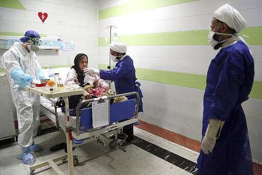 FILE &#151; In this Saturday, March 7, 2020 file photo, a cleric, right, assists a medic treating a patient infected with the new coronavirus, at a hospital in Qom, about 80 miles (125 kilometers) south of the capital Tehran, Iran. Nine out of 10 cases of the virus in the Middle East come from the Islamic Republic. Fears remain that Iran may be underreporting its cases. Days of denials gave the virus time to spread as the country marked the 41st anniversary of its 1979 Islamic Revolution with mass demonstrations. For most people, the new coronavirus causes only mild or moderate symptoms. For some it can cause more severe illness. (Mohammad Ali Marizad/Rasa News Agency via AP, File)