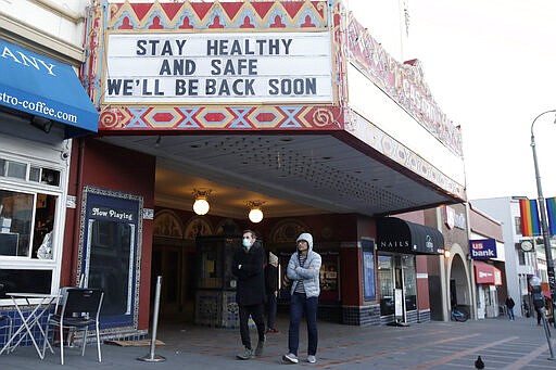 A man wears a mask while walking under the marquee of The Castro Theatre in San Francisco, Monday, March 16, 2020. Officials in six San Francisco Bay Area counties issued a shelter-in-place mandate Monday affecting nearly 7 million people, including the city of San Francisco itself. The order says residents must stay inside and venture out only for necessities for three weeks starting Tuesday in a desperate attempt by officials to curb the spread of the novel coronavirus. (AP Photo/Jeff Chiu)