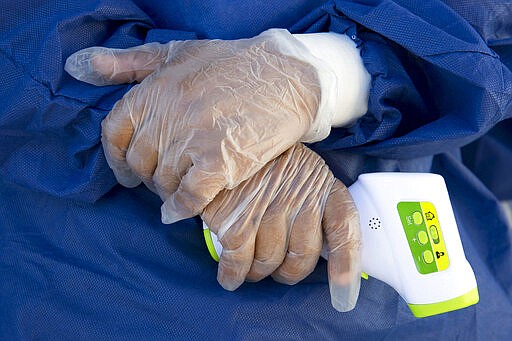 A nurse holds a temperature gun used to measure people's temperatures, a precaution against the spread of the new coronavirus, while processing incoming Haitians at the border crossing  Jimani, in the Dominican Republic, Tuesday, March 17, 2020. For most people, the new coronavirus causes only mild or moderate symptoms, such as fever and cough. For some, especially older adults and people with existing health problems, it can cause more severe illness, including pneumonia. (AP Photo/Dieu Nalio Chery)