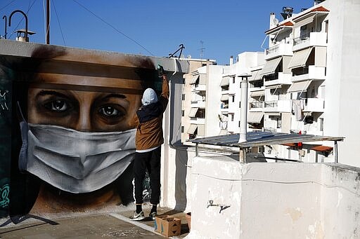 S.F., a 16-year-old Greek graffiti artist, spray-paints a design, a woman wearing a face mask referring to protection against coronavirus, on the roof of his apartment block in Athens, Tuesday, March 17, 2020. Greece has imposed a wide range of public safety measures to try and contain the coronavirus outbreak, including school and store closures. The vast majority of people recover from the new coronavirus. According to the World Health Organization, most people recover in about two to six weeks, depending on the severity of the illness. (AP Photo/Thanassis Stavrakis)