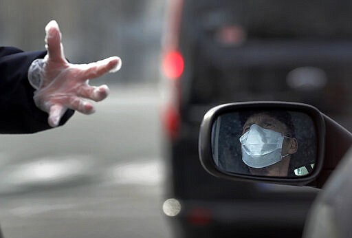 A police officer speaks to a car driver in Paris, Tuesday, March 17, 2020. French President Emmanuel Macron said that starting on Tuesday, people would be allowed to leave the place they live only for necessary activities such as shopping for food, going to work or taking a walk. For most people, the new coronavirus causes only mild or moderate symptoms. For some it can cause more severe illness. (AP Photo/Christophe Ena)