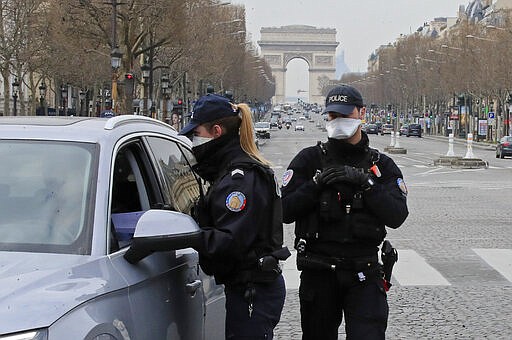 Police officers wearing protective masks check papers at a control point at the Champs Elysees avenue in Paris, Tuesday, March 17, 2020. France is imposing nationwide restrictions on how far from their homes people can go and for what purpose as part of the country's strategy to stop the spread of the new coronavirus. For most people, the new coronavirus causes only mild or moderate symptoms, such as fever and cough. For some, especially older adults and people with existing health problems, it can cause more severe illness, including pneumonia. (AP Photo/Michel Euler)