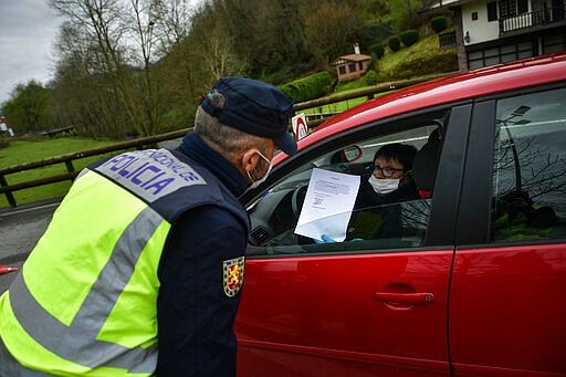 Spanish police officers controls the identity of a woman close to the border between Spain and France near the Pyrenees Spanish village of Dantxarinea, northern Spain, Tuesday, March 17, 2020. Spain is restoring border controls and severely restricting who can enter the country. Interior Minister Fernando Grande-Marlaska announced Monday that only Spaniards or residents in Spain, people who work just across the border or who have a compelling need will be allowed through. For most people, the new coronavirus causes only mild or moderate symptoms. For some it can cause more severe illness. (AP Photo/Alvaro Barrientos)