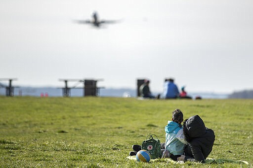 Visitors to Gravelly Point watch as a plane takes off from Ronald Reagan Washington National Airport, Monday, March 16, 2020, in Arlington, Va. (AP Photo/Andrew Harnik)