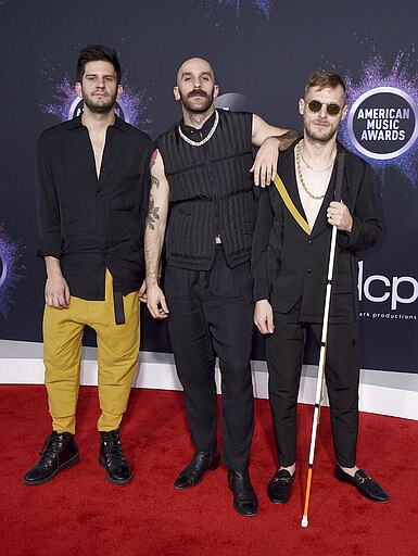 FILE - In this Nov. 24, 2019 file photo, Adam Levin, from left, Sam Harris, and Casey Harris, of X Ambassadors, arrive at the American Music Awards in Los Angeles. The rock trio X Ambassadors have been bouncing around the world as several of their concert dates were canceled due to the coronavirus. First was China. Then Milan. And while setting up in Poland for a performance, they were told to shut down. They eventually arrived in Lithuania and made it home to Los Angeles on Thursday as President Donald Trump announced a travel ban. (Photo by Jordan Strauss/Invision/AP, File)