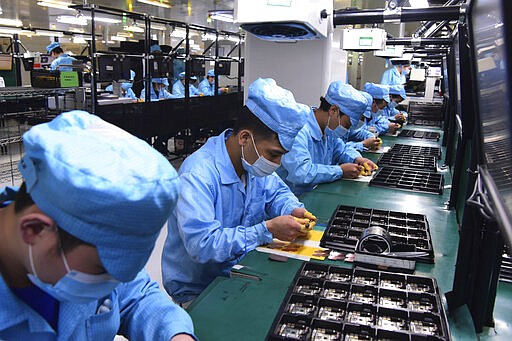 In this Feb. 13, 2020, photo released by Xinhua News Agency, workers wearing masks labor at a factory for Chinese telecommunications company OPPO in Dongguan, in southern China's Guangdong Province. Factories in China, struggling to reopen after the coronavirus shut down the economy, face a new threat from U.S. anti-disease controls that might disrupt the flow of microchips and other components they need. For most people, the new coronavirus causes only mild or moderate symptoms. For some it can cause more severe illness. (Chen Yuxuan/Xinhua via AP)