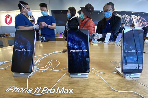 In this Thursday, March 5, 2020, photo, workers attend to shoppers at an Apple store in Beijing. Factories in China, struggling to reopen after the coronavirus shut down the economy, face a new threat from U.S. anti-disease controls that might disrupt the flow of microchips and other components they need. For most people, the new coronavirus causes only mild or moderate symptoms. For some it can cause more severe illness. (AP Photo/Ng Han Guan)