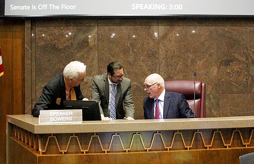 Republican Rep. John Kavanaugh, left, and GOP Chief of Staff Michael Hunter, center, listen to GOP House Speaker Rusty Bowers, right, before a floor session at the Capitol in Phoenix, Wednesday, March 18, 2020. The House hopes to quickly pass a bare-bones budget and send it to the Senate before adjourning until the coronavirus crisis ebbs. (AP Photo/Bob Christie)